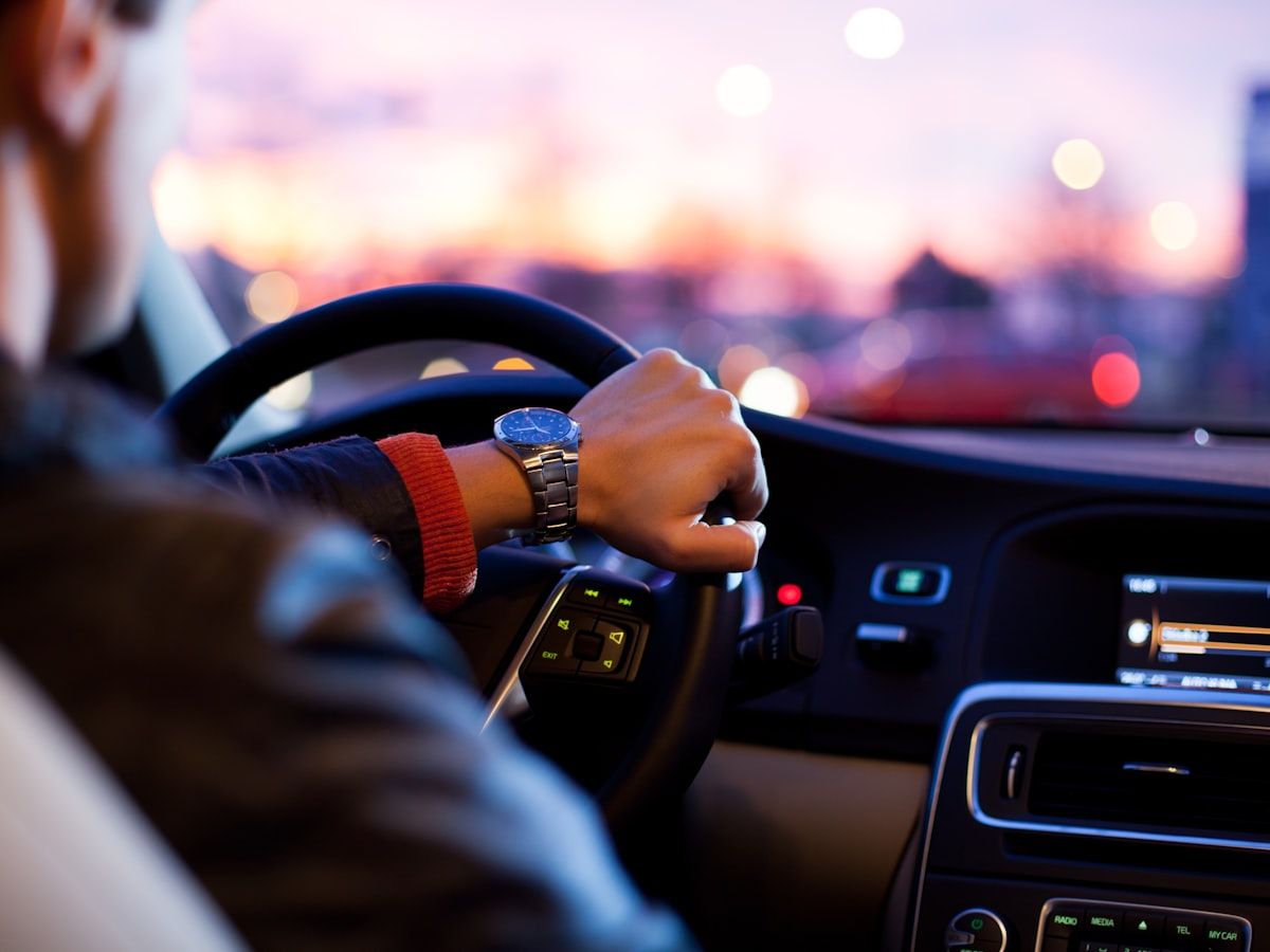 A driver's hands on the steering wheel at dusk