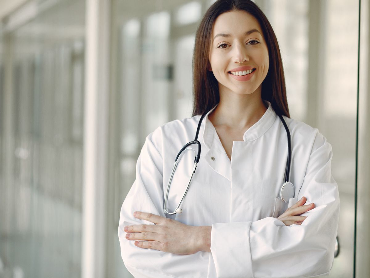 A smiling doctor with a stethoscope in a bright clinic hallway